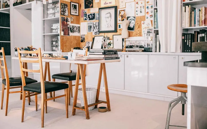 A studio desk with shelves of reference material