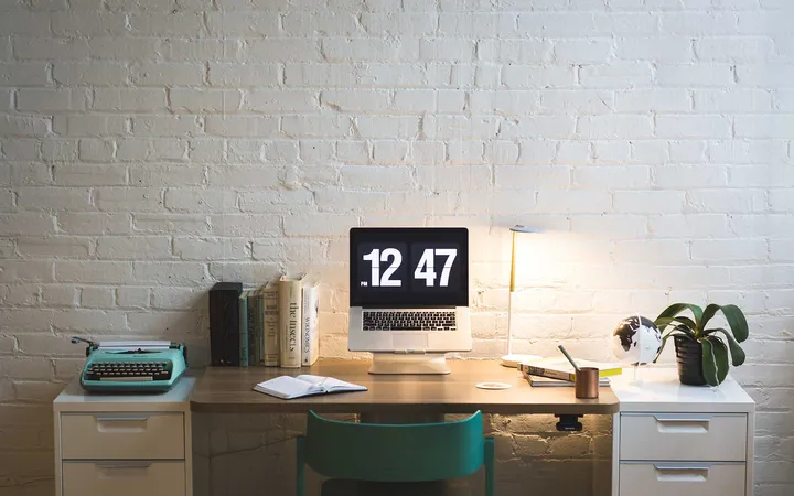 A tidy desk with a desktop clock reading 12:47