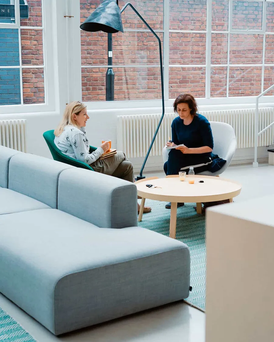 Two people in conversation in a bright studio lounge