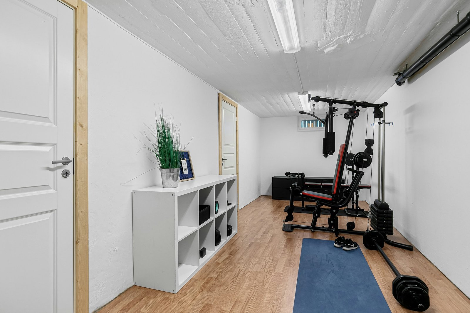 Bright spare-room home gym with a multi-station, a bench and a blue exercise mat
