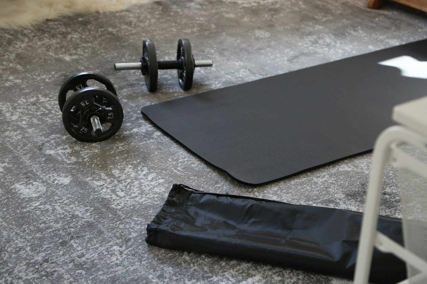 Dumbbells and a black exercise mat on the floor