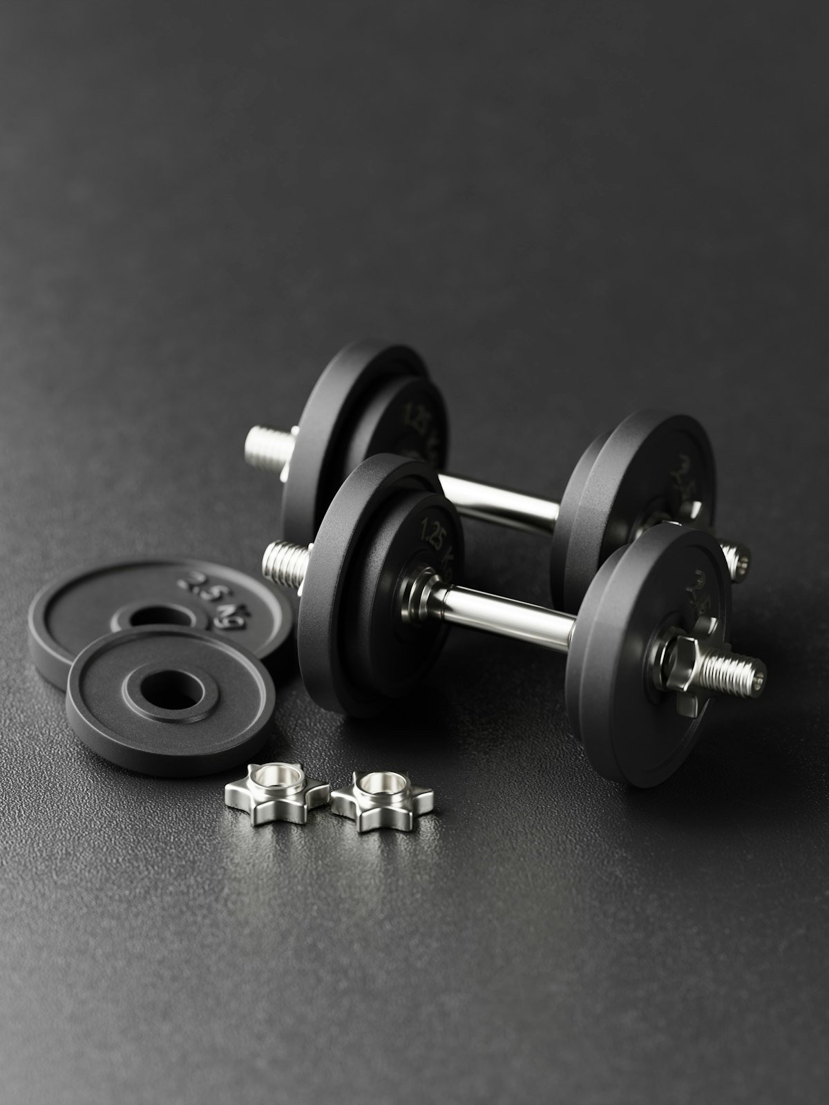 Pair of plate-loaded dumbbells on a dark surface